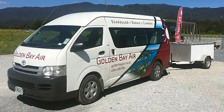 Golden Bay Air shuttle van, with bike trailer attached is parked at Golden Bay Air Terminal at Takaka Airport