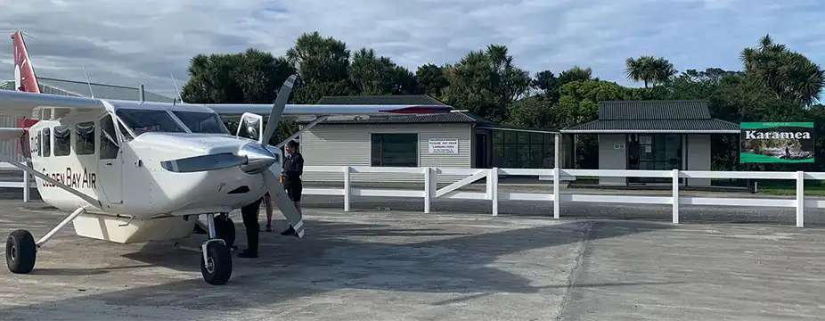 Golden Bay Air Airvan aircraft parked on ramp in front of Karamea Airport passenger building