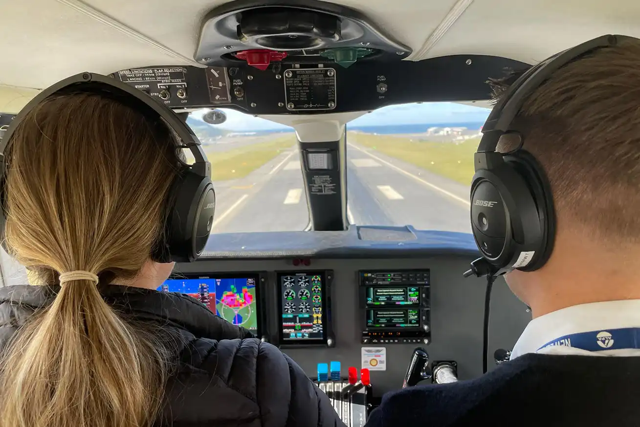 View from behind pilots in cockpit of Golden Bay Air Islander on approach to land with Wellington Airport runway visable through windscreen