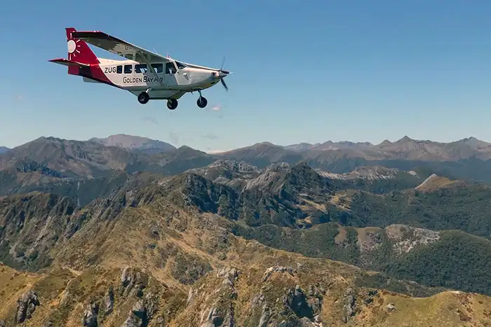 Golden Bay Air Airvan flying over Kahurangi National Park with complex pattern of mountain ranges on the horizon