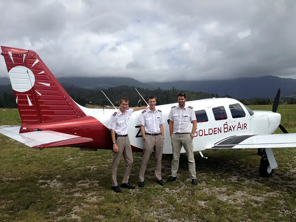Golden Bay Air pilots posing by Saratoga ZK-ZIG in new livery